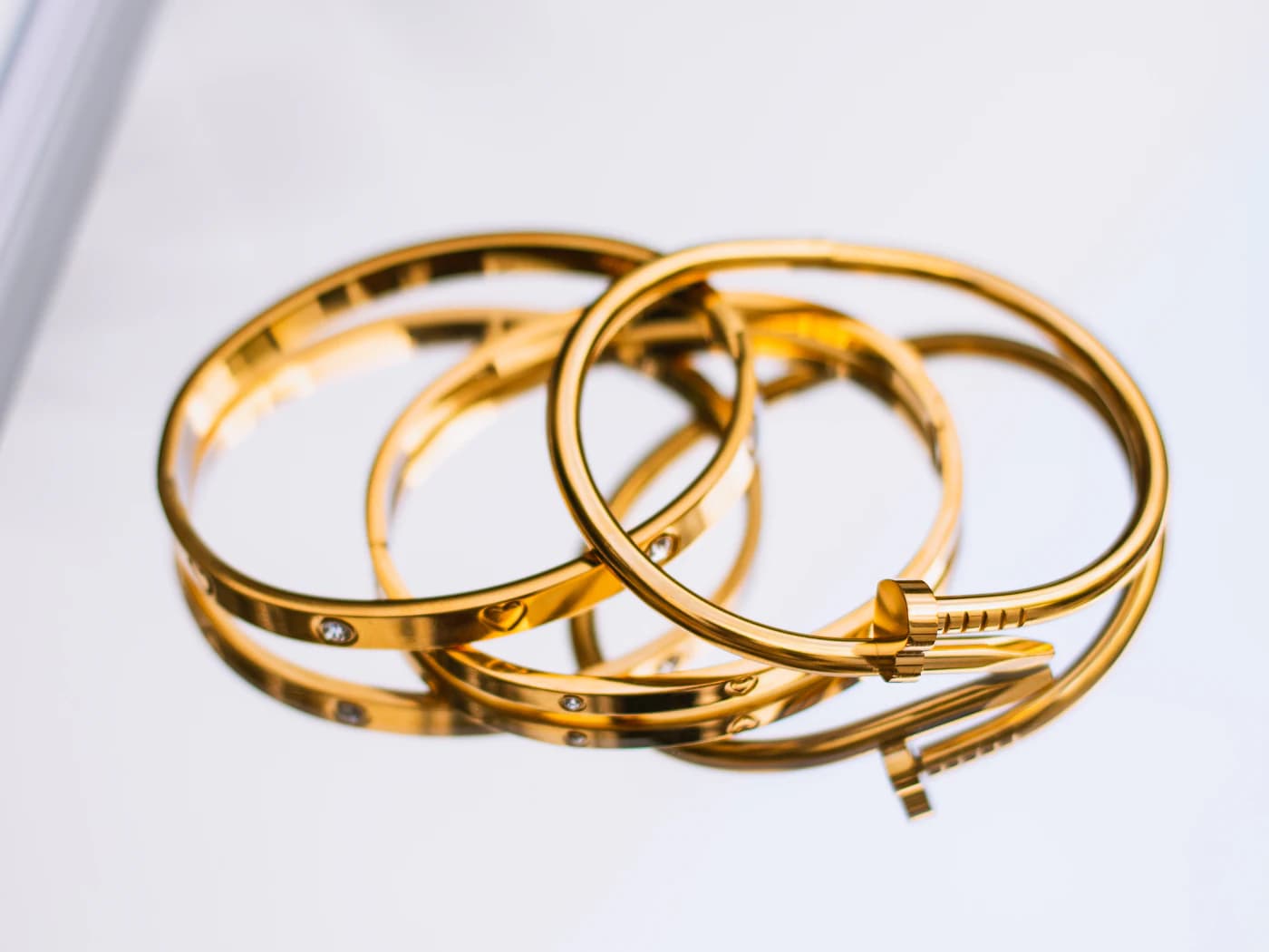Stacked gold bangles on a reflective surface (illustrative photo)