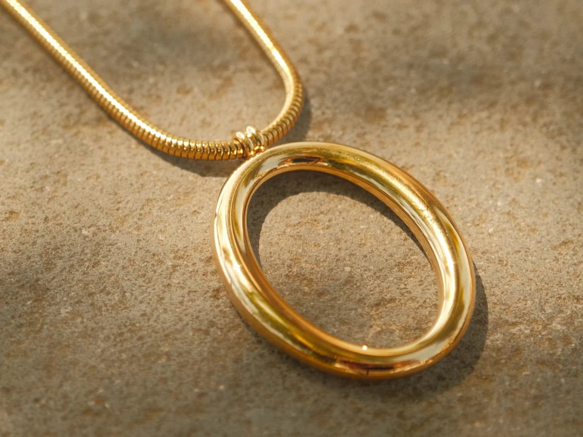 Gold bangles and a chain on a warm, textured surface (illustrative photo)