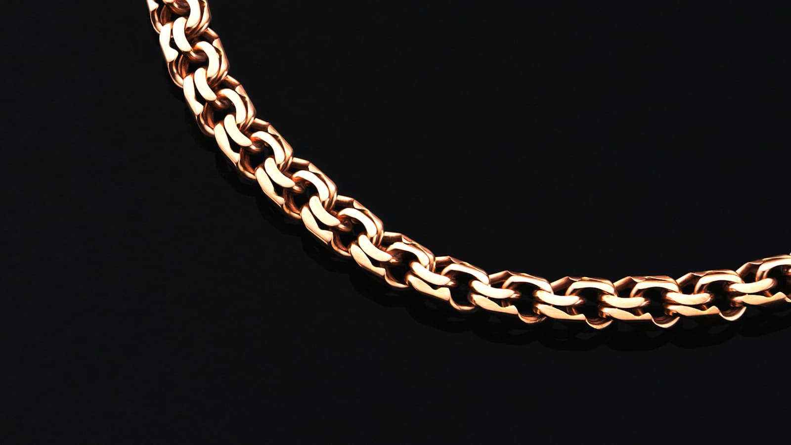 Close-up of a rose-gold chain on a black background (illustrative photo)