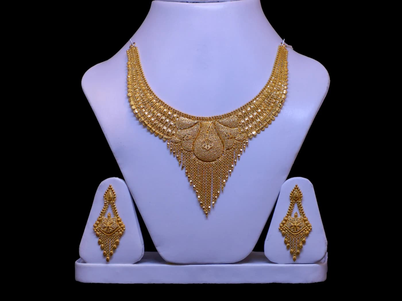 Gold choker necklace and earring set on a display stand (illustrative photo)